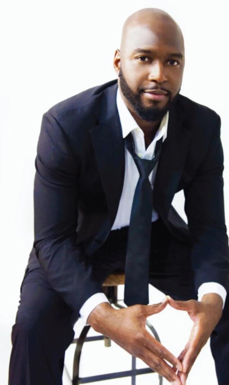 Mario West in a suit, seated portrait